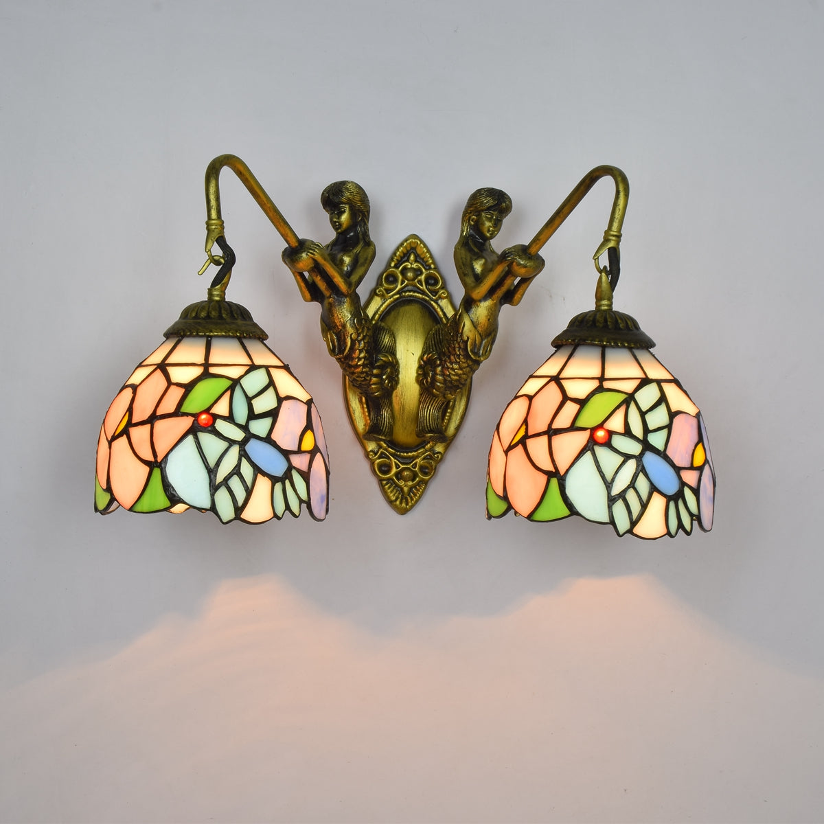 Tiffany-style wall sconce in stained glass and brass, featuring mermaids.