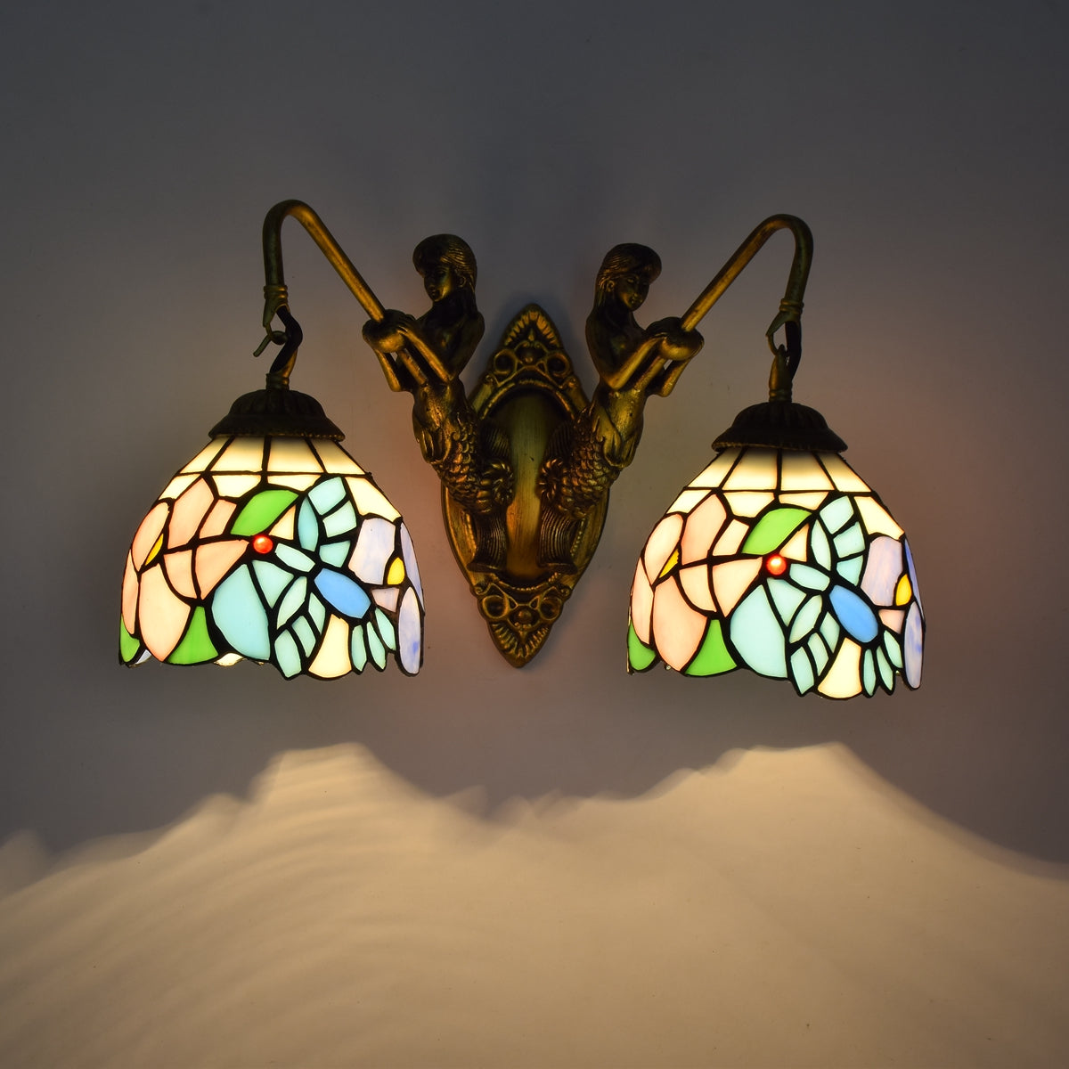 Tiffany-style wall sconce in stained glass and brass, featuring mermaids.